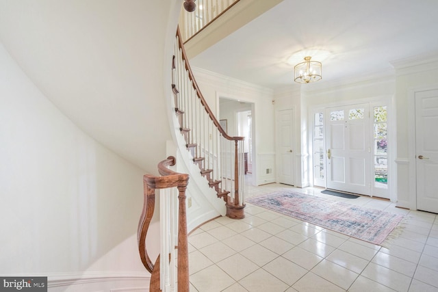 tiled entryway featuring crown molding and a chandelier