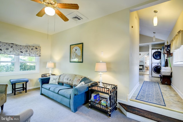 living room featuring stacked washer / drying machine, light colored carpet, ceiling fan, and lofted ceiling