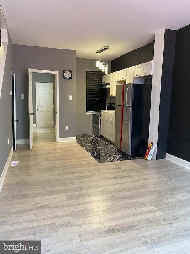 kitchen featuring light hardwood / wood-style flooring, white cabinetry, pendant lighting, and stainless steel appliances