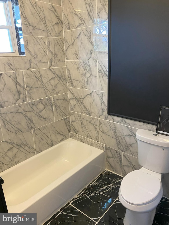 bathroom featuring toilet, tile patterned floors, and tile walls