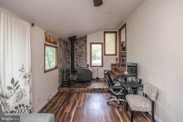 office space featuring dark wood-type flooring, vaulted ceiling, a healthy amount of sunlight, and a wood stove