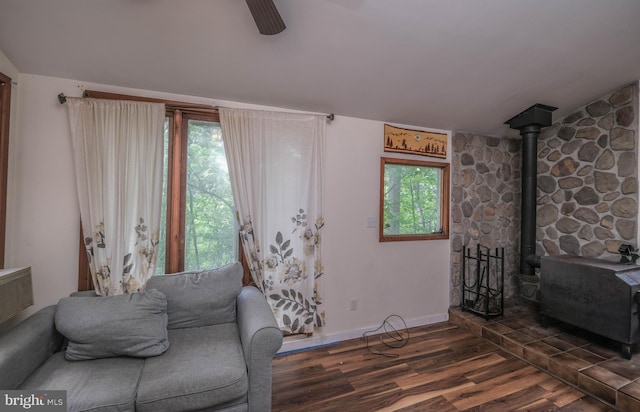 living room with ceiling fan, dark hardwood / wood-style flooring, and a wood stove