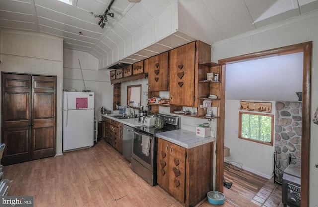 kitchen with rail lighting, sink, tile countertops, light hardwood / wood-style flooring, and appliances with stainless steel finishes