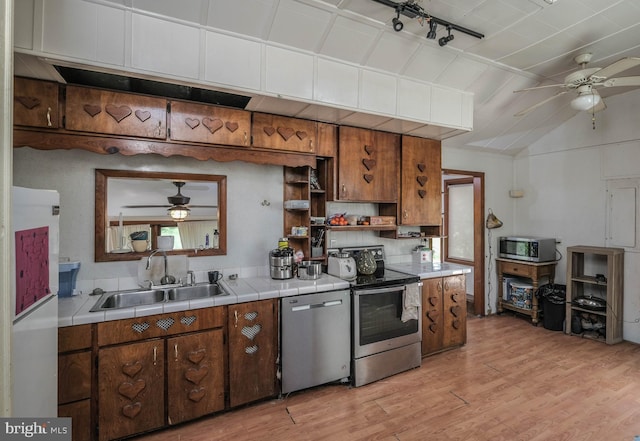 kitchen featuring sink, tile countertops, appliances with stainless steel finishes, ceiling fan, and light hardwood / wood-style floors