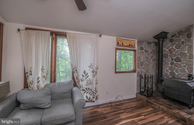 living area with ceiling fan, dark hardwood / wood-style floors, and a wood stove