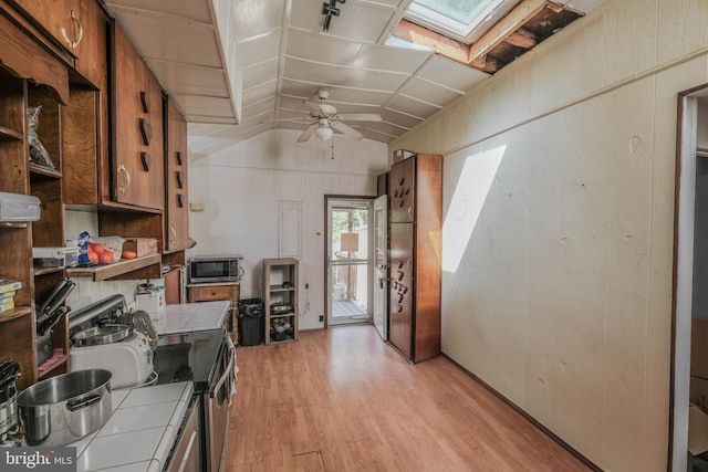 office space with vaulted ceiling with skylight, ceiling fan, and light wood-type flooring