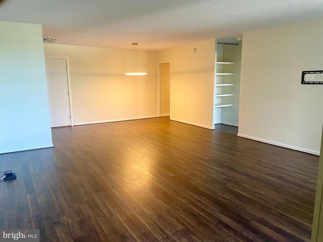 empty room with a textured ceiling and dark wood-type flooring