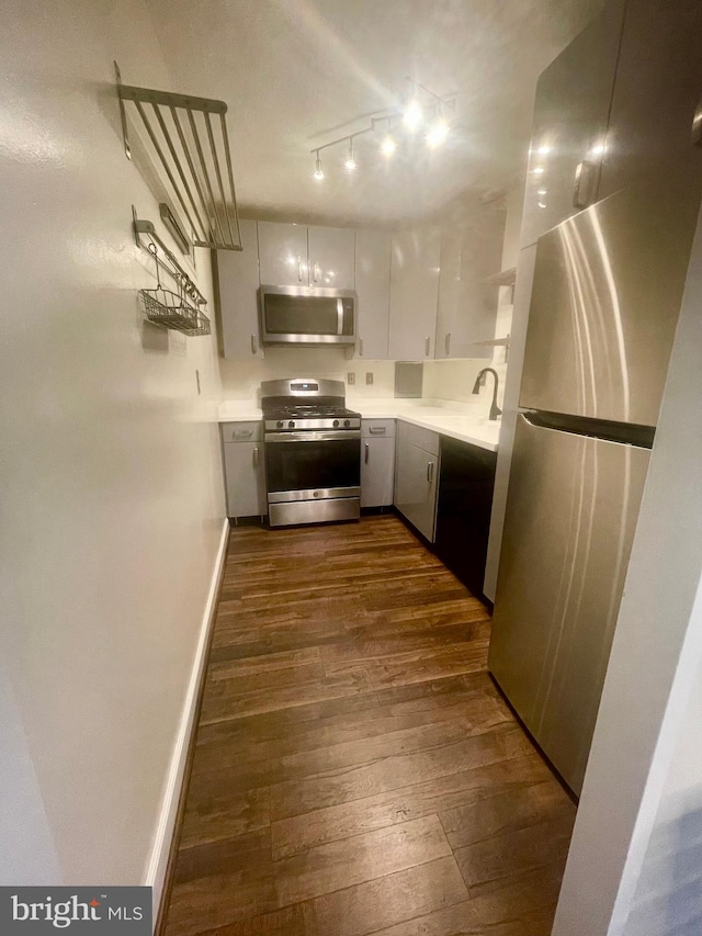 kitchen featuring stainless steel appliances, dark hardwood / wood-style floors, white cabinets, and track lighting