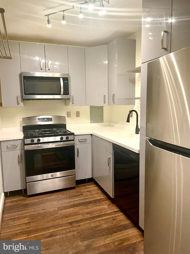 kitchen featuring appliances with stainless steel finishes, dark hardwood / wood-style flooring, sink, and a textured ceiling