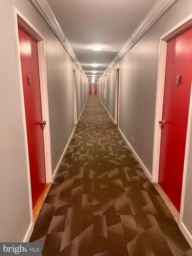 corridor featuring crown molding and dark carpet