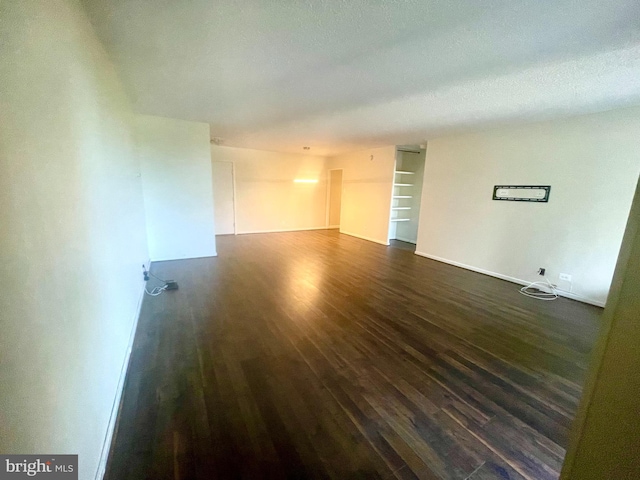 spare room with a textured ceiling and dark hardwood / wood-style floors