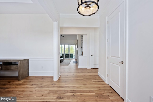 hallway featuring crown molding and light hardwood / wood-style flooring