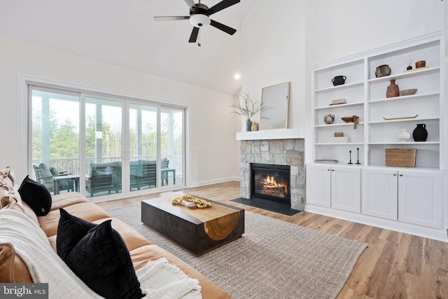 living room featuring ceiling fan, a fireplace, light hardwood / wood-style flooring, and a healthy amount of sunlight