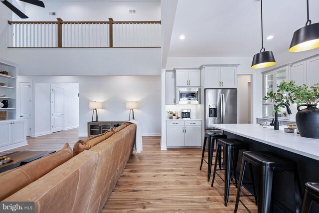 living room with sink, light hardwood / wood-style flooring, and a high ceiling