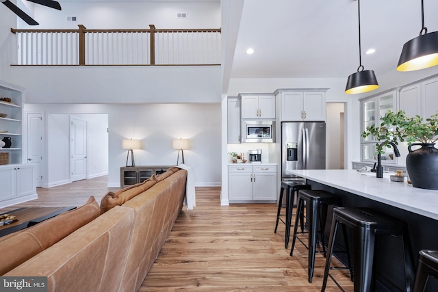 kitchen with pendant lighting, white cabinetry, stainless steel appliances, and a kitchen bar