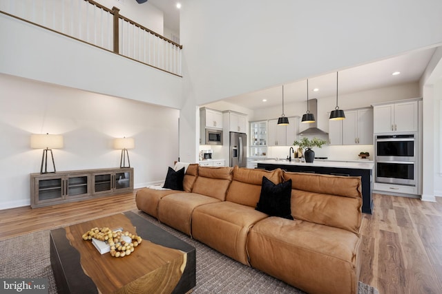 living room with a towering ceiling and light wood-type flooring