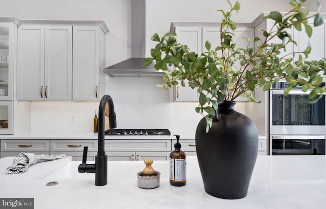 details with white cabinetry and wall chimney exhaust hood