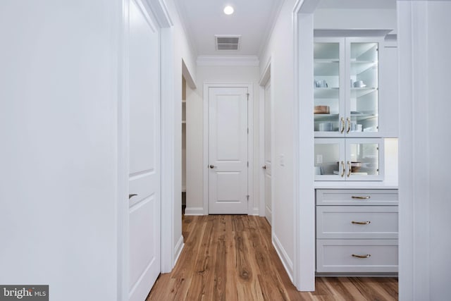 hallway featuring crown molding and light hardwood / wood-style floors