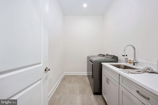 laundry room with independent washer and dryer, light hardwood / wood-style floors, sink, and cabinets