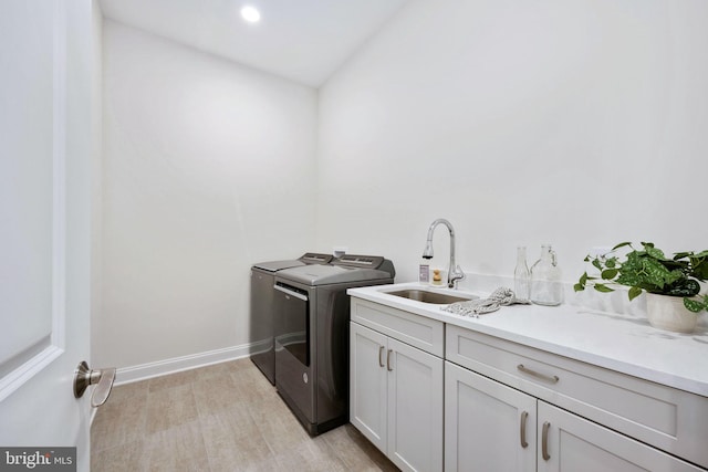 washroom with sink, washing machine and dryer, and cabinets