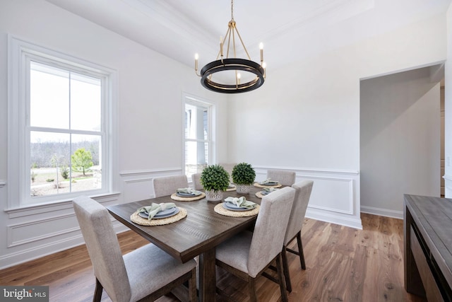 dining space featuring light wood-type flooring, a notable chandelier, and a tray ceiling