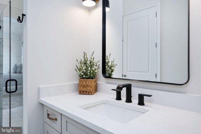 bathroom with a shower with shower door and vanity