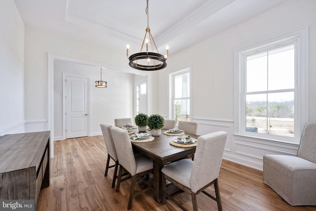 dining area with hardwood / wood-style flooring, a notable chandelier, and a tray ceiling