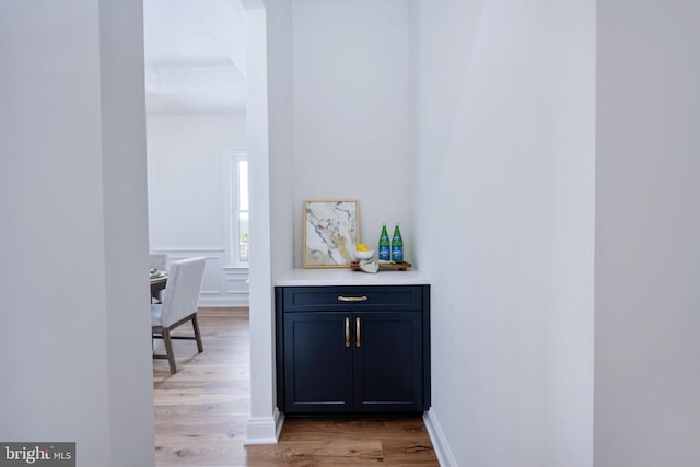 bar with ornamental molding and light wood-type flooring