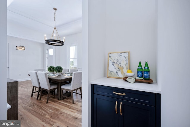 dining room with crown molding, light hardwood / wood-style floors, and a notable chandelier