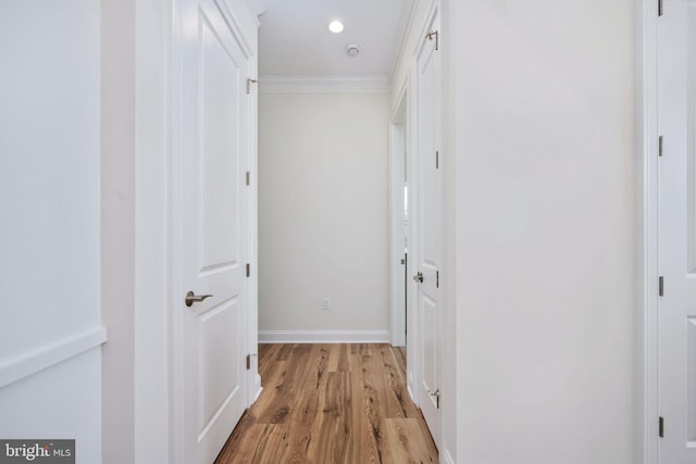 corridor with light wood-type flooring and crown molding