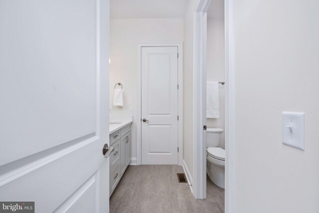 bathroom with toilet, hardwood / wood-style flooring, and vanity