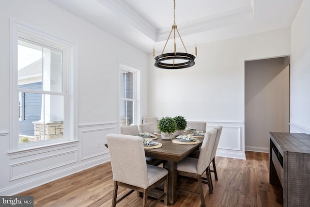 dining room with light hardwood / wood-style floors and a raised ceiling