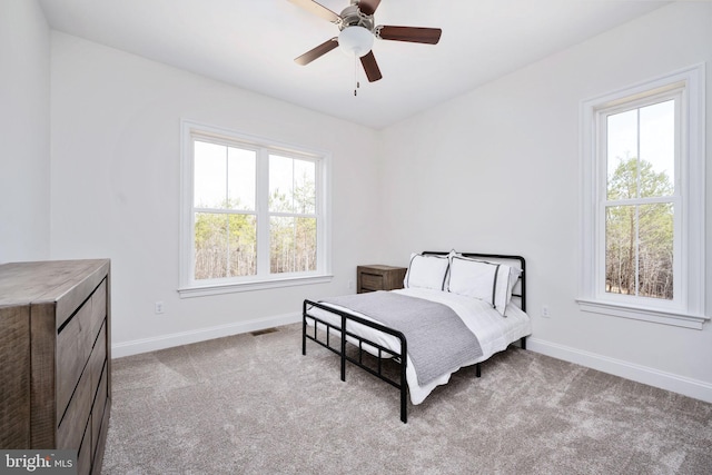 carpeted bedroom with multiple windows and ceiling fan