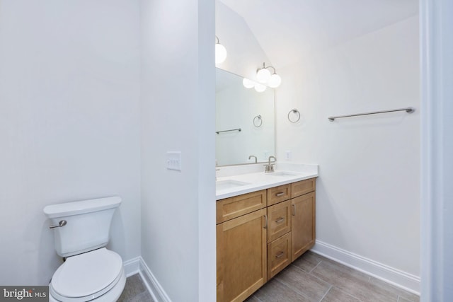 bathroom featuring toilet, dual vanity, vaulted ceiling, and tile patterned floors