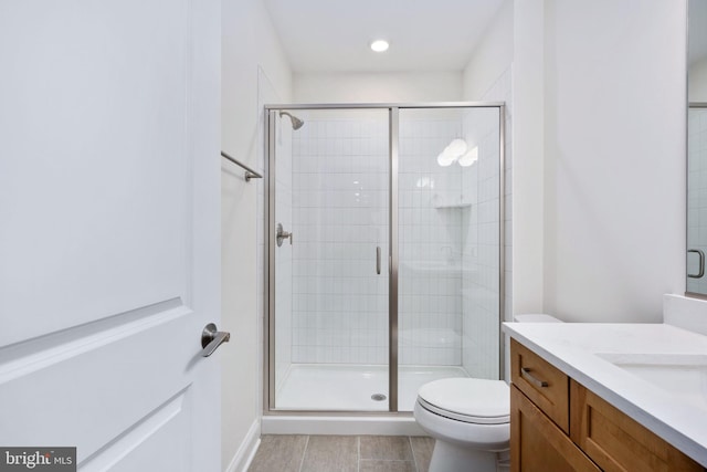 bathroom with tile patterned floors, a shower with door, vanity, and toilet