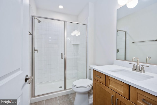 bathroom with tile patterned flooring, a shower with shower door, vanity, and toilet