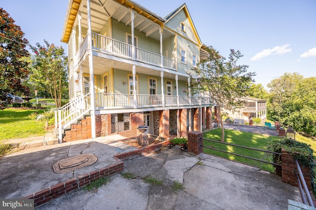 back of property with a yard, covered porch, and a balcony