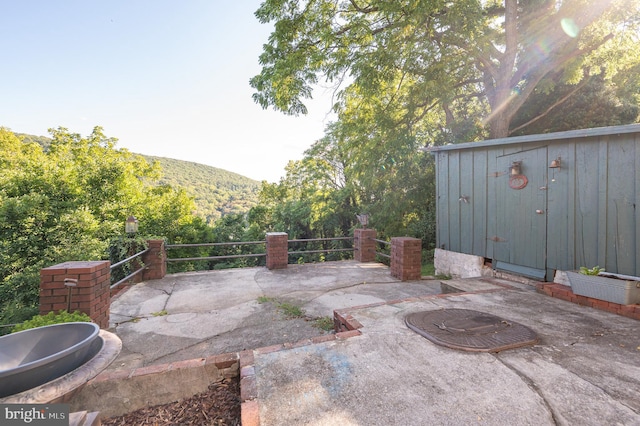 view of patio featuring a mountain view, an outdoor structure, and a storage shed