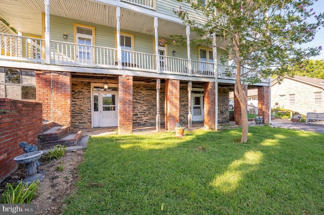 back of house with brick siding and a lawn