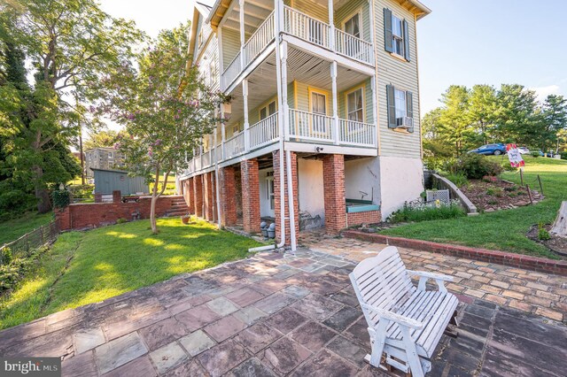 rear view of house featuring a balcony, a yard, and a patio area