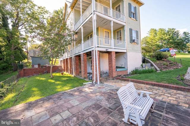 back of property with a patio area, a yard, a balcony, and brick siding