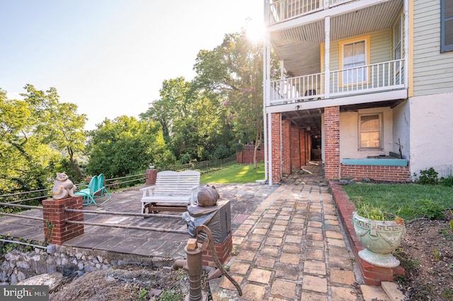 view of patio featuring fence and a balcony