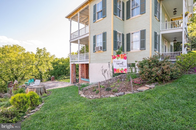 view of property exterior featuring a yard, cooling unit, a patio, and a balcony