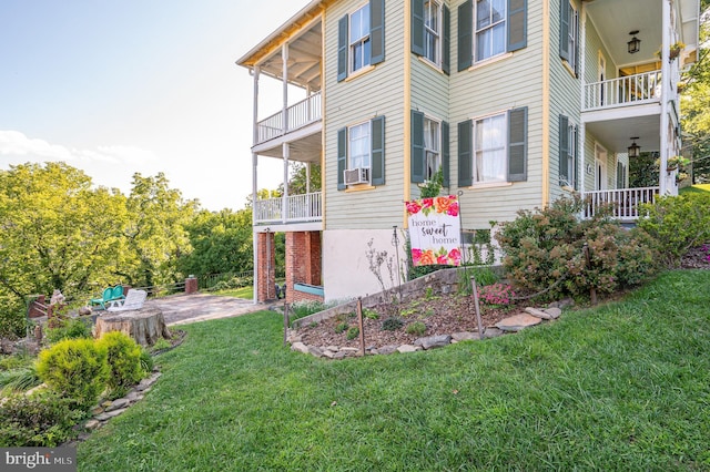 view of property exterior featuring a patio, a yard, and a balcony