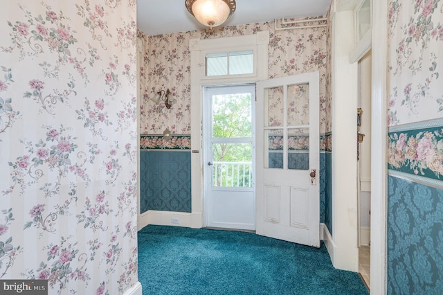 doorway to outside with dark colored carpet, baseboards, and wallpapered walls