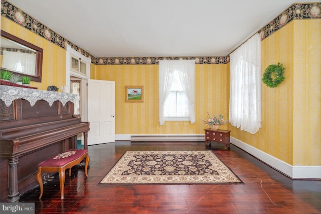 sitting room featuring wallpapered walls, baseboards, baseboard heating, and dark wood-type flooring