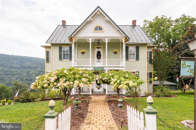 victorian-style house featuring a porch and a front lawn