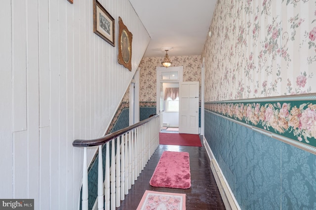 hall featuring dark wood-style floors, a wainscoted wall, and wallpapered walls