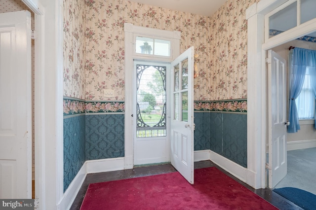 doorway with a healthy amount of sunlight, wallpapered walls, and wainscoting