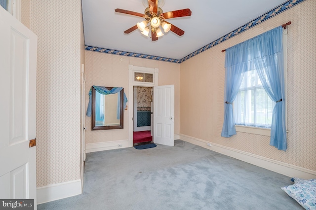 unfurnished room with a ceiling fan, carpet flooring, baseboards, and wallpapered walls